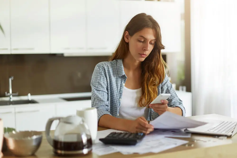 Young woman sitting at a desk with receipts checking allowable business expenses from OnlyFans earnings in the UK.