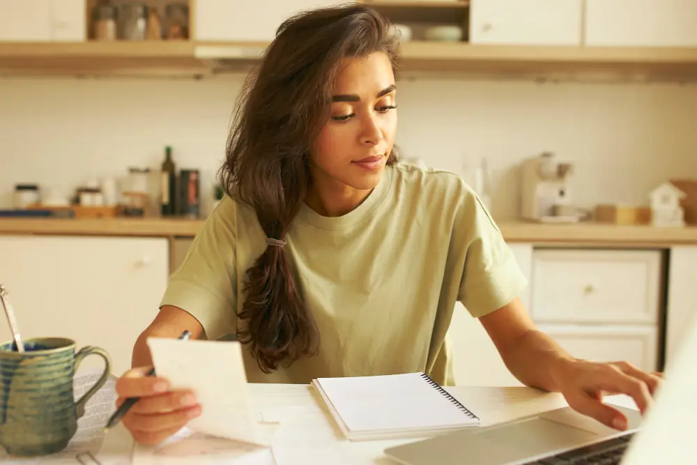 OnlyFans creator doing bookkeeping and tracking UK income on a laptop at her desk.