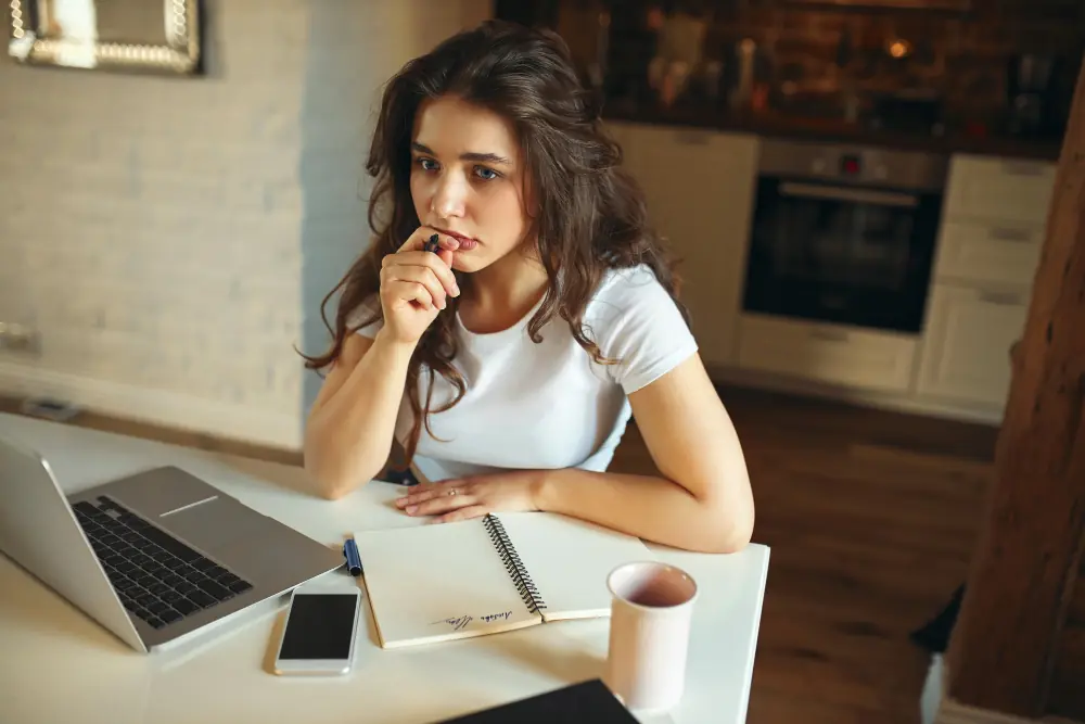 Thoughtful OnlyFans creator at laptop choosing between sole trader or limited company.